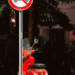 Verbodsbord voor scooters met een geparkeerde rode scooter erachter