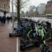 Volle deelvervoerhub met deelscooters en deelfietsen in een drukke Nederlandse binnenstad
